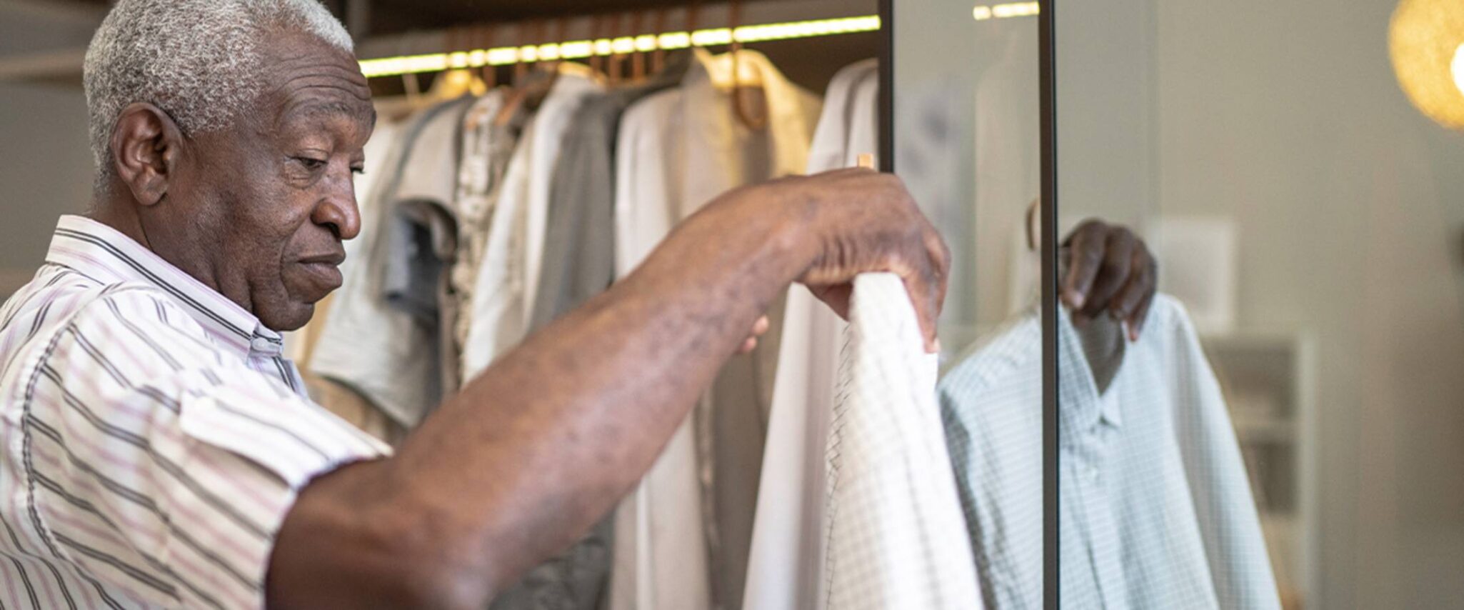 A senior man looks at clothes hanging in the closet