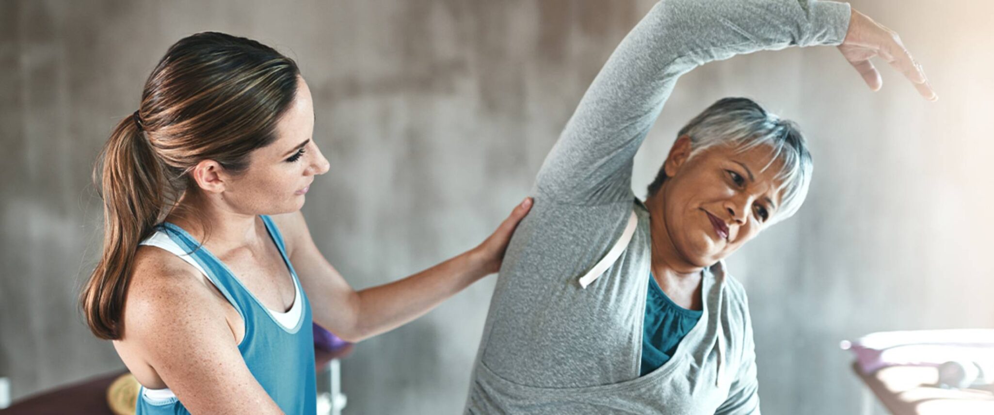Senior woman stretching with the help of her physical therapist