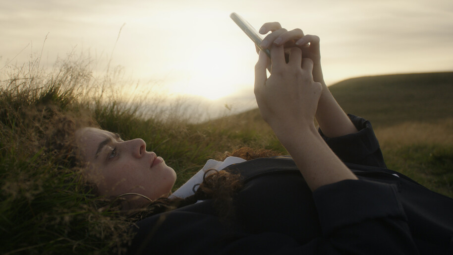 girl lying in the grass looking at her phone