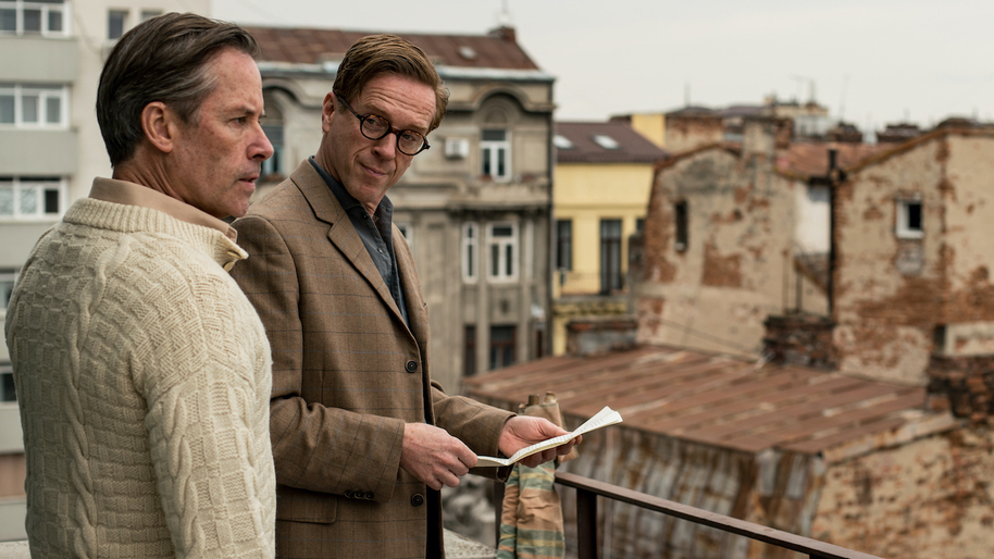 Guy Pearce and Damian Lewis stood talking on a rooftop in A Spy Among Friends