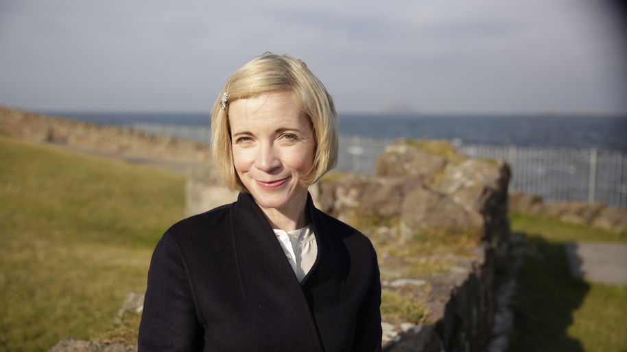 Lucy Worsley standing in a field