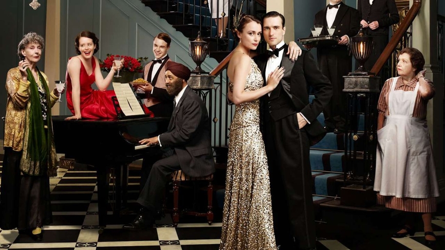 A group of men and women stood in 1930s aristocratic clothing in a grand lobby