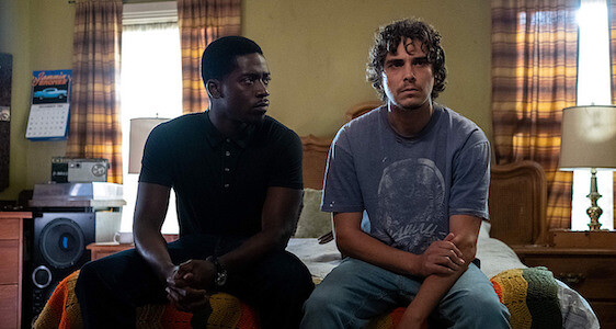 Two young adults sitting on edge of bed