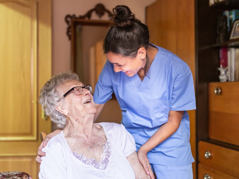 Senior woman and home care nurse laughing together.