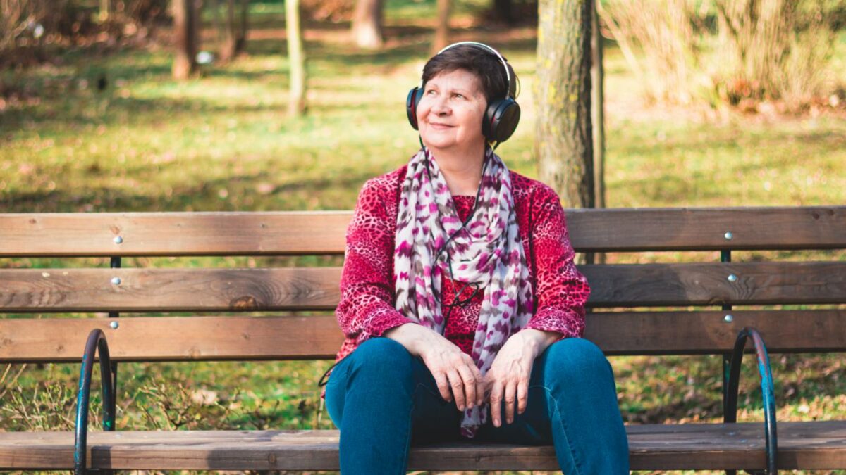 senior lady listening to music with headphones on for music therapy