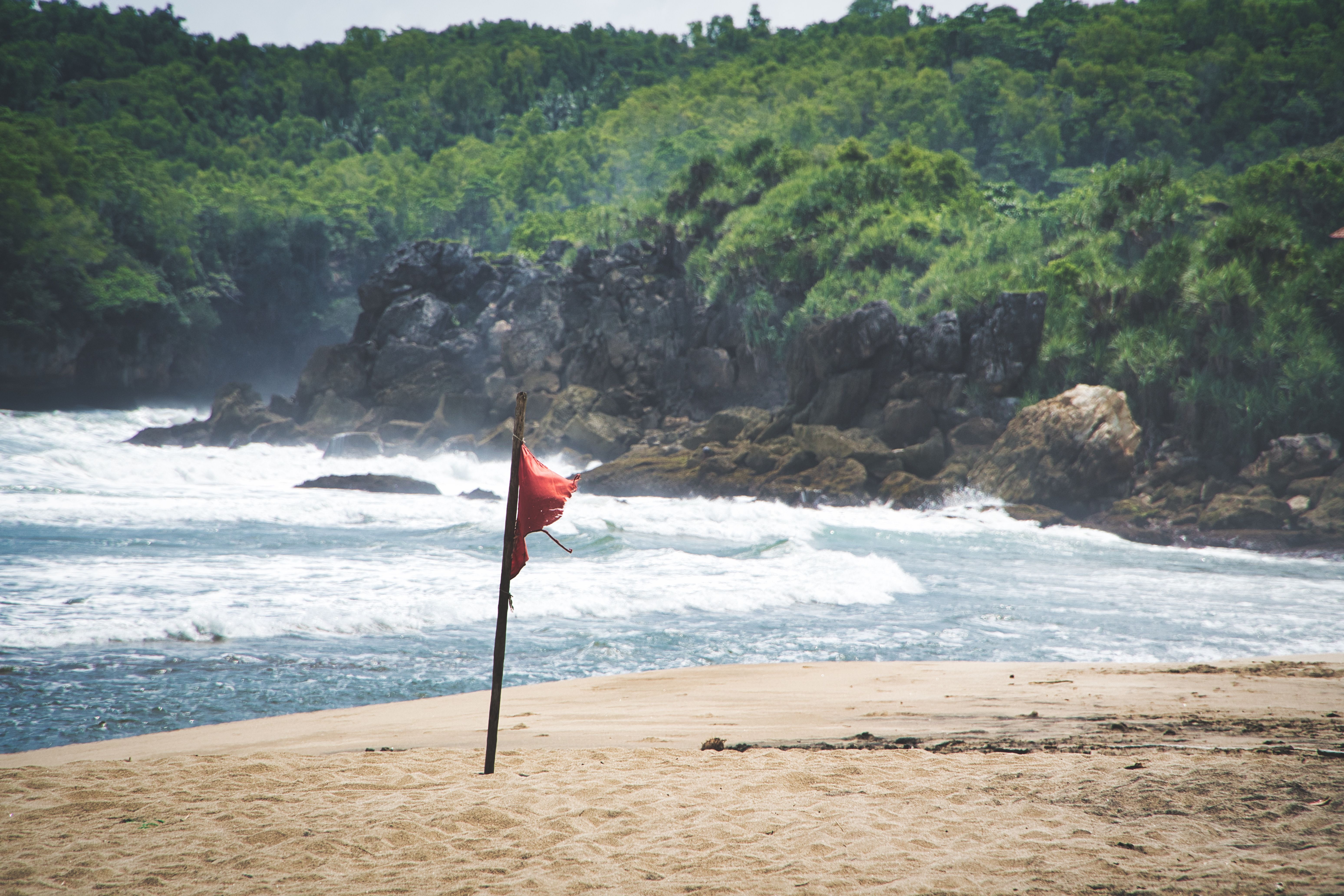 Red warning flag on a rough Phuket beach during monsoon season