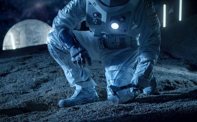 Astronaut bending down on moons surface