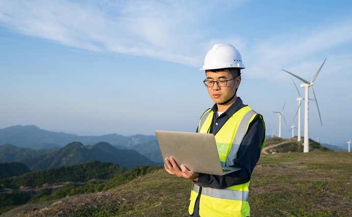 Man looking at clipboard with wind turbine in background