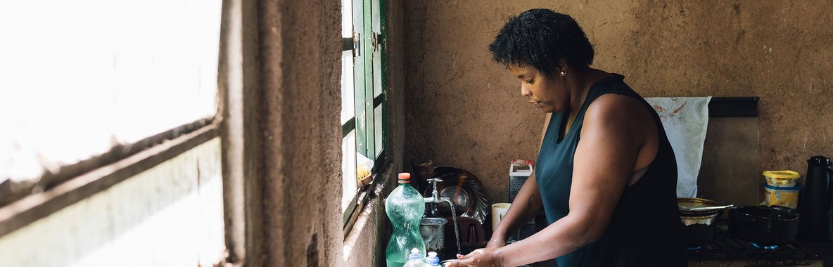 Poor woman doing washing in sink