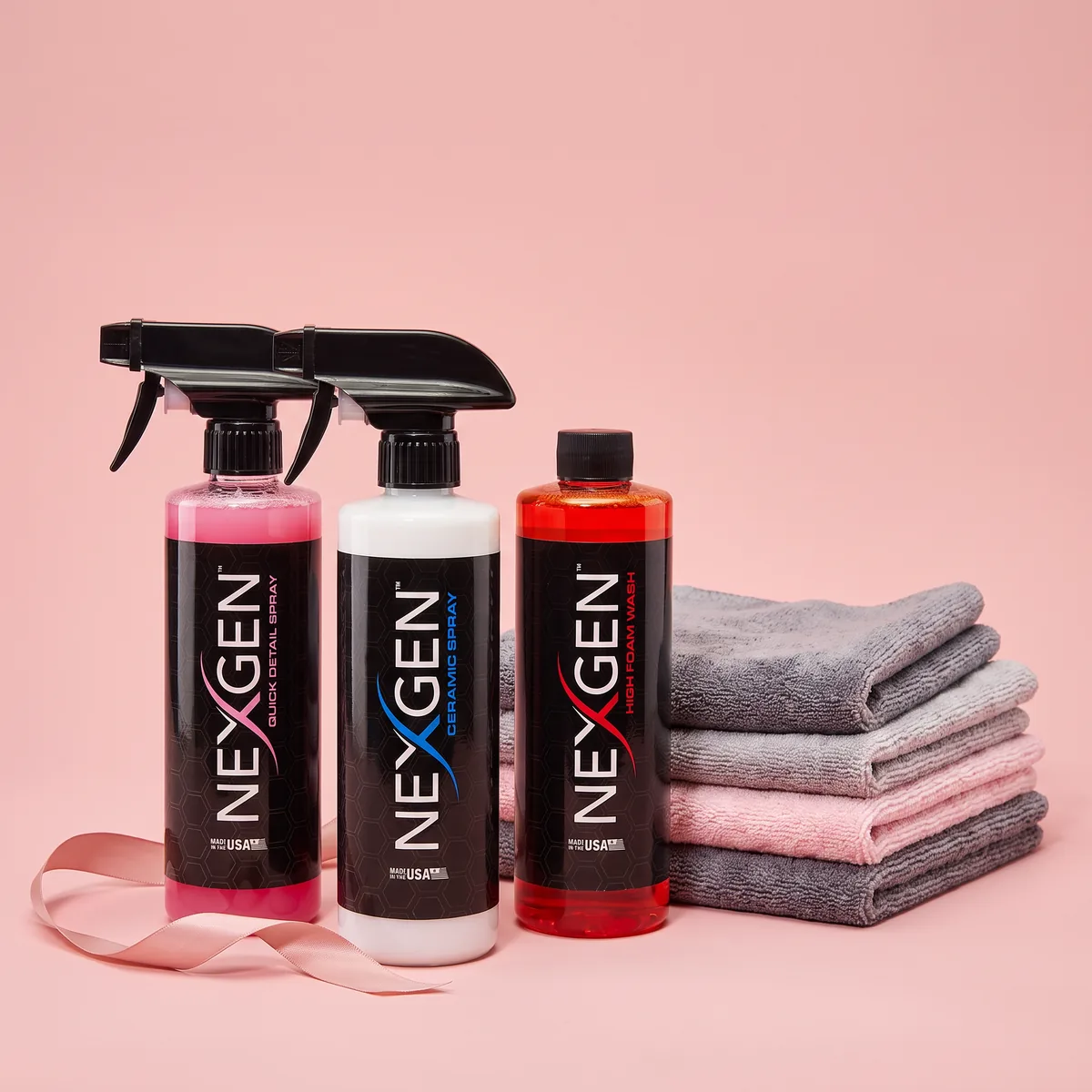 The Race for the Cure bundle: Ceramic Spray, High Foam Wash and Quick Detail Spray beside a stack of microfiber towels and a pink ribbon.