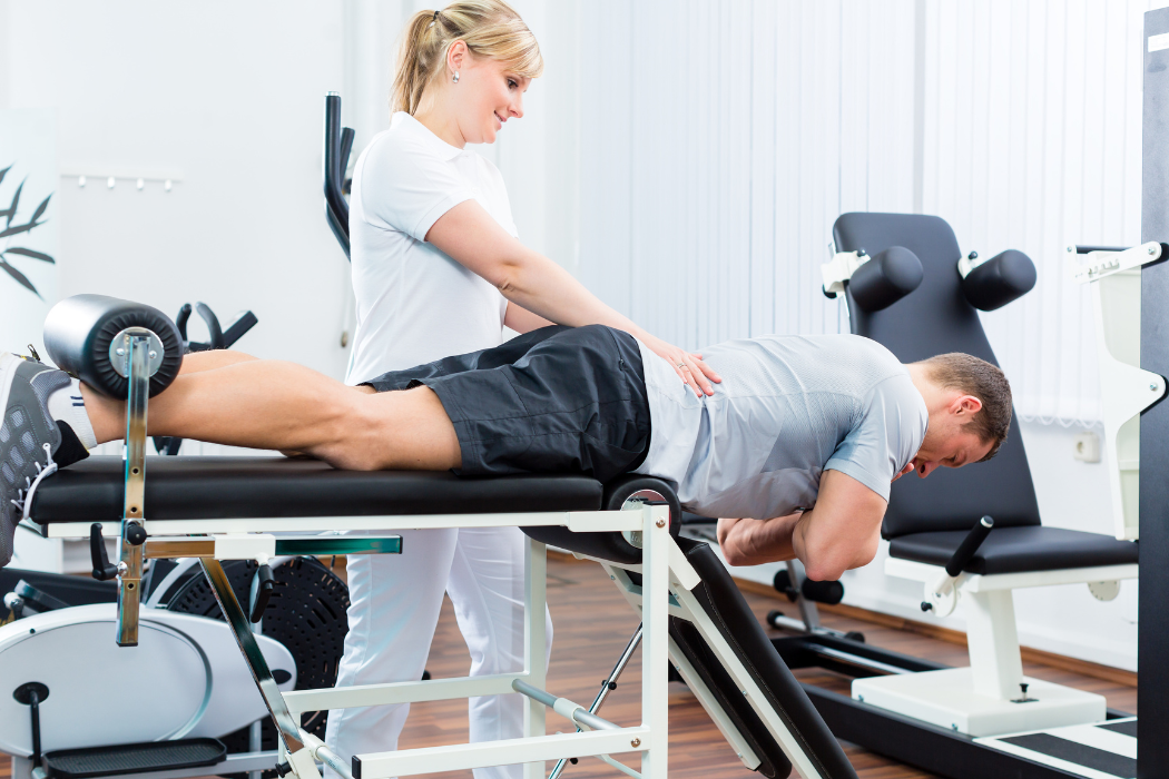 Fyzioterapeutka aplikuje léčebné techniky na pacienta ležícího na zdravotním lůžku ve fyzioterapeutické místnosti.