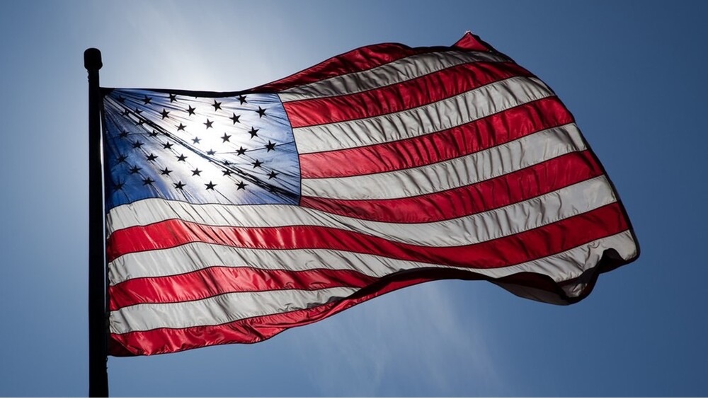 An American Flag flies against a blue sky.