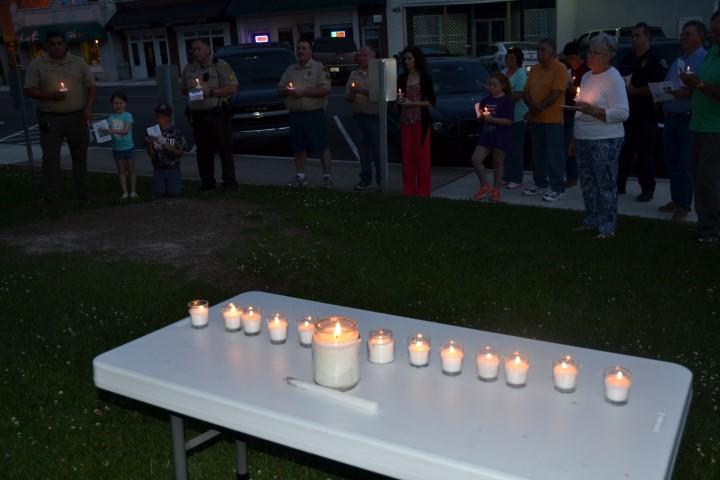 The candlelight vigil with participants in the background at dusk.