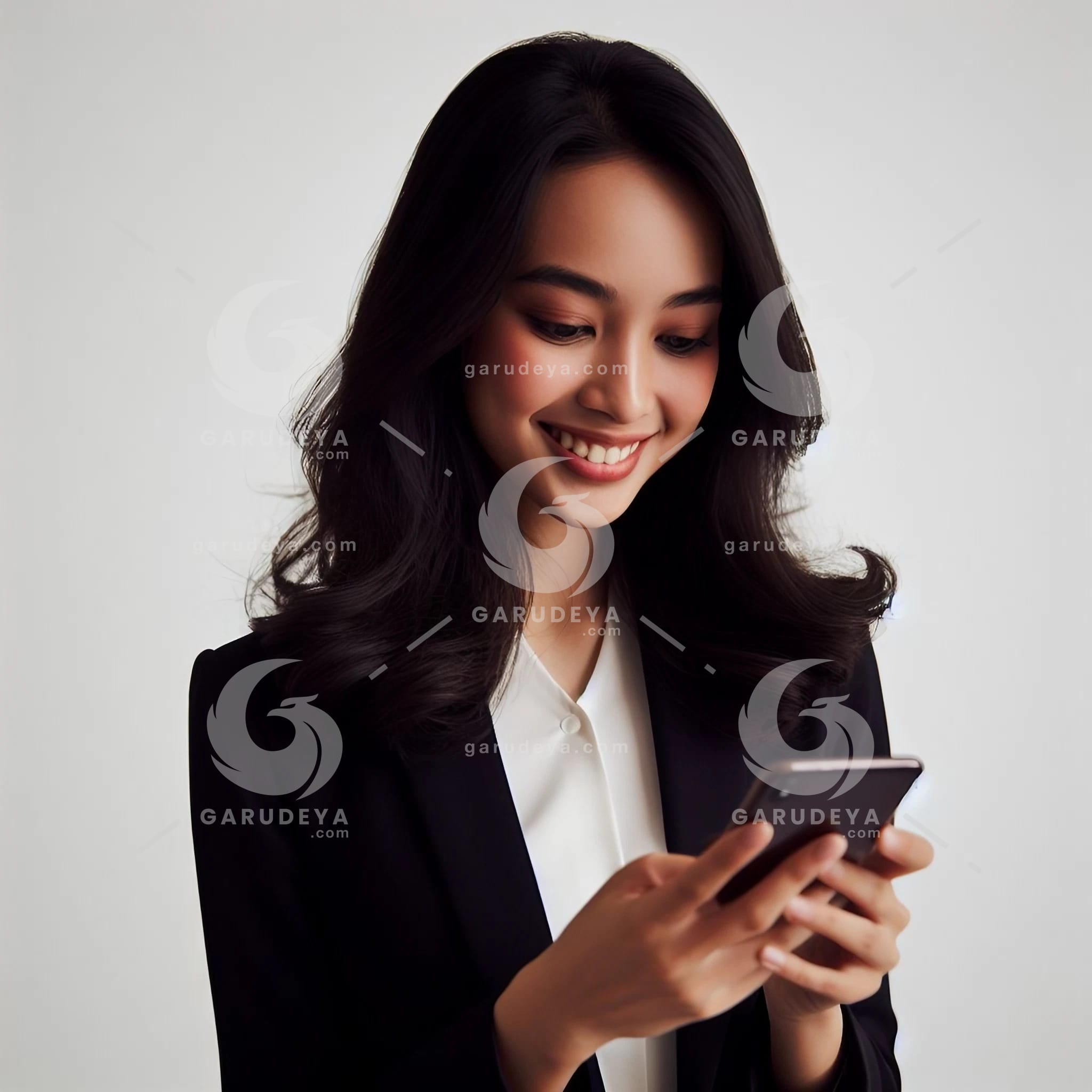 beautiful young Indonesian woman in formal clothes, looking at a cellphone screen with a cheerful expression-525897520