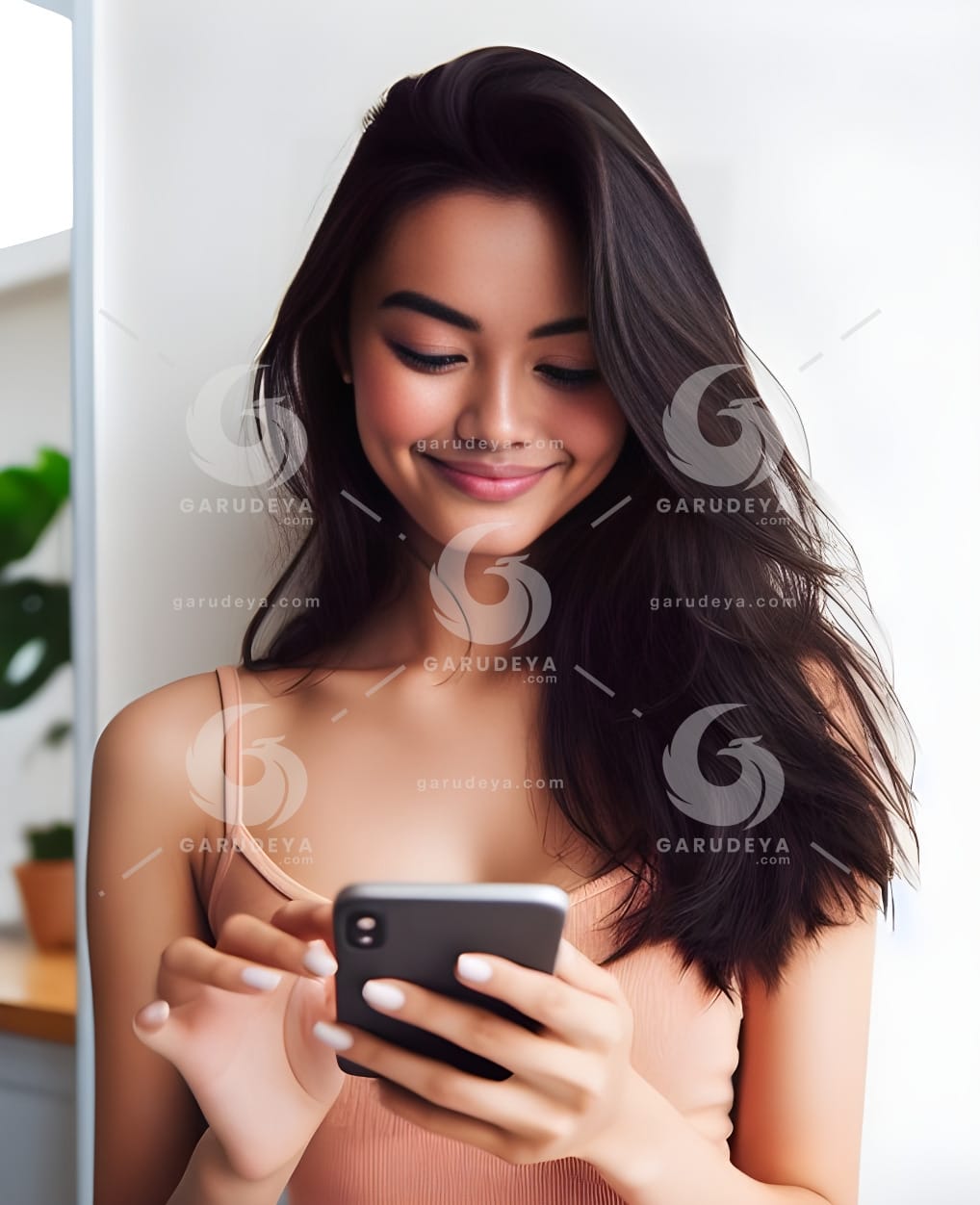 beautiful young Indonesian woman looking at a cellphone screen with a cheerful expression-692288