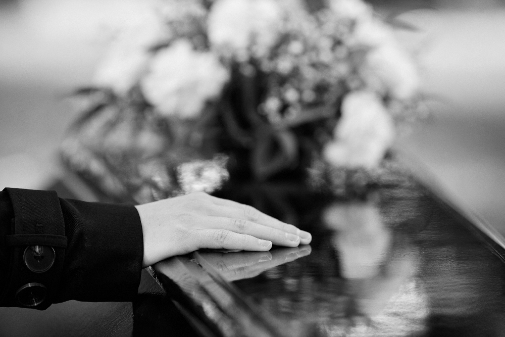 image of hand on coffin