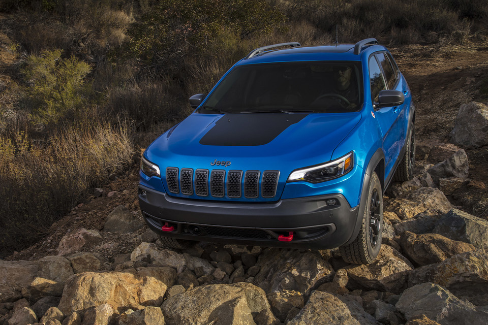 Blue Jeep Cherokee Trailhawk driving over rocks 