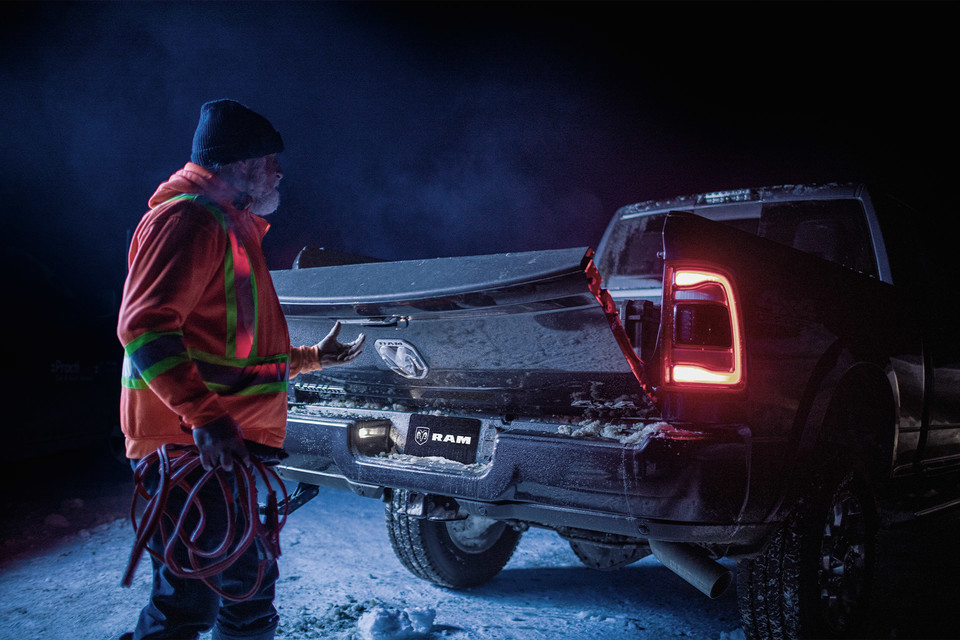 Man opening Ram truck noise dampening tailgate at night 