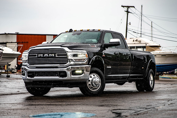 2022 Ram 3500 Dually Black parked on wet concrete with boats in the back