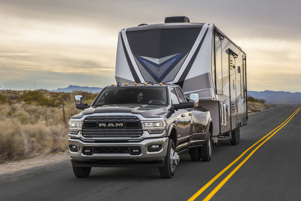 Grey Ram 3500 towing a trailer in a desert highway setting at dusk