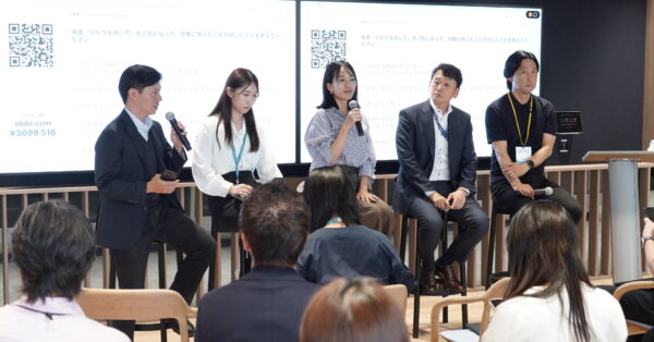 イベント会場でパネリスト5人が登壇し、映画上映後のトークセッションを来場者が見守っている。