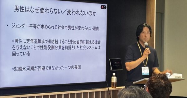 スクリーンに資料を映し、男性育休やジェンダー平等をテーマに講演する登壇者。