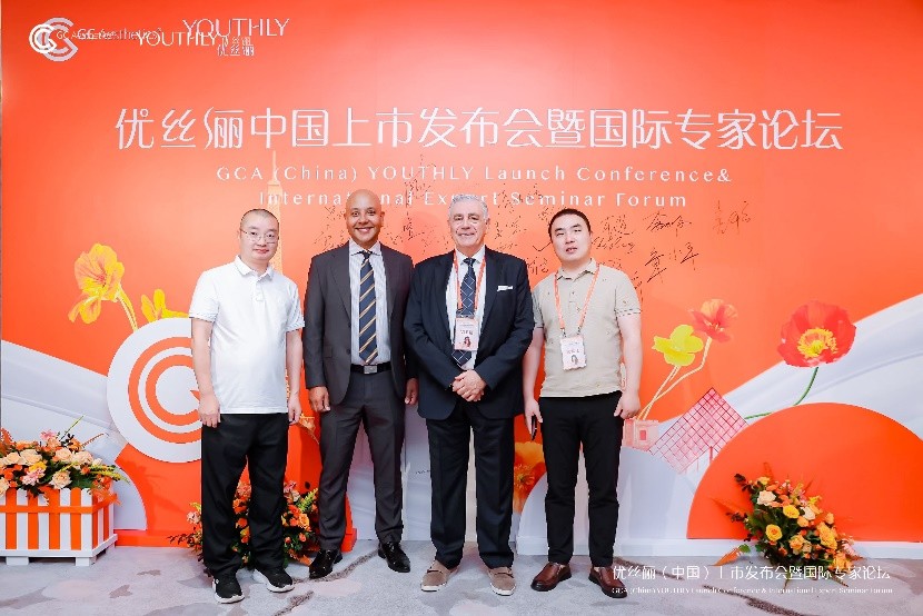 A group of men standing in front of a red wall

Description automatically generated