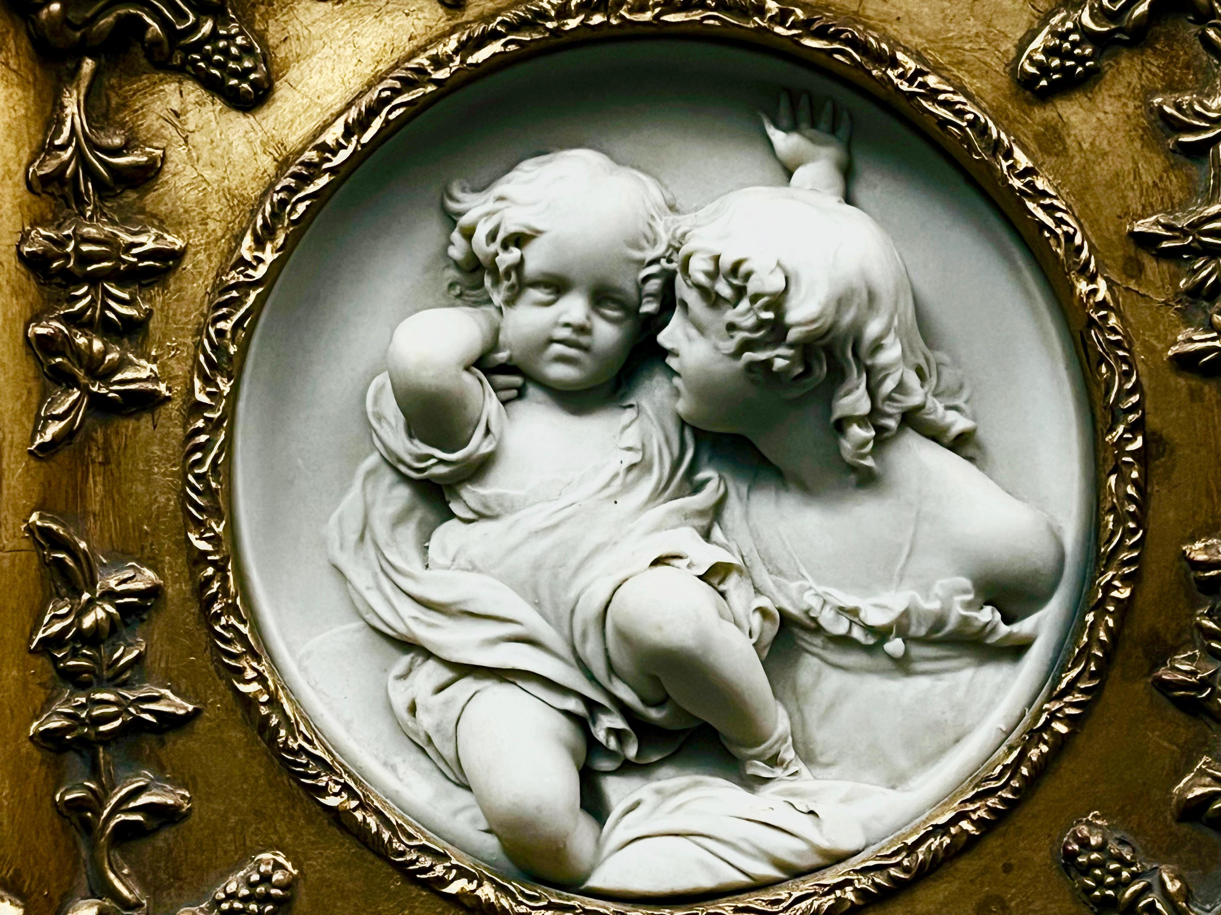 Dekoracyjny  owalny medalion zdobiony płaskorzeźbą z dwójką dziewcząt