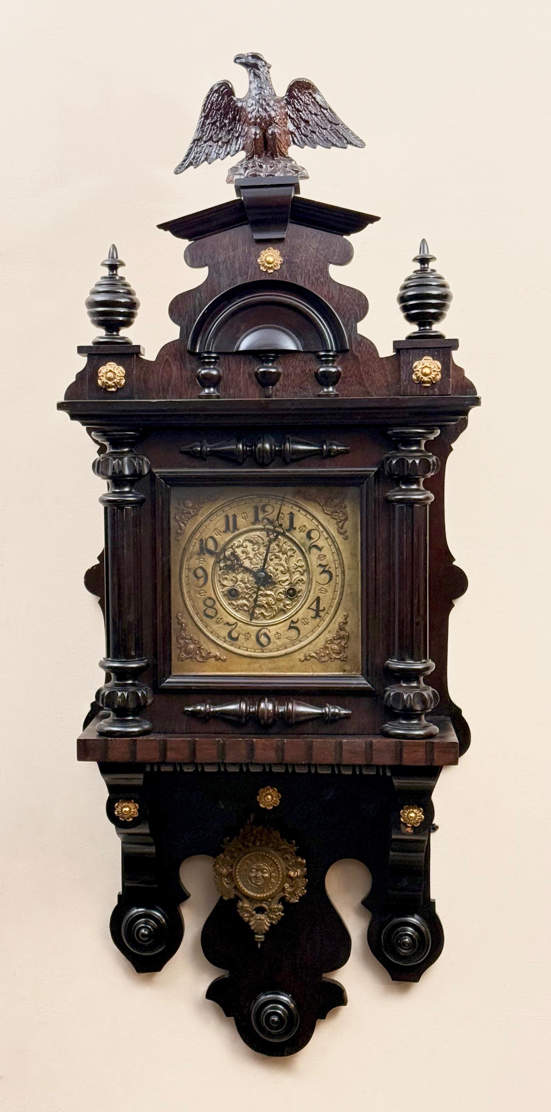 Dekoracyjny zegar ścienny zdobiony na szczycie orłem