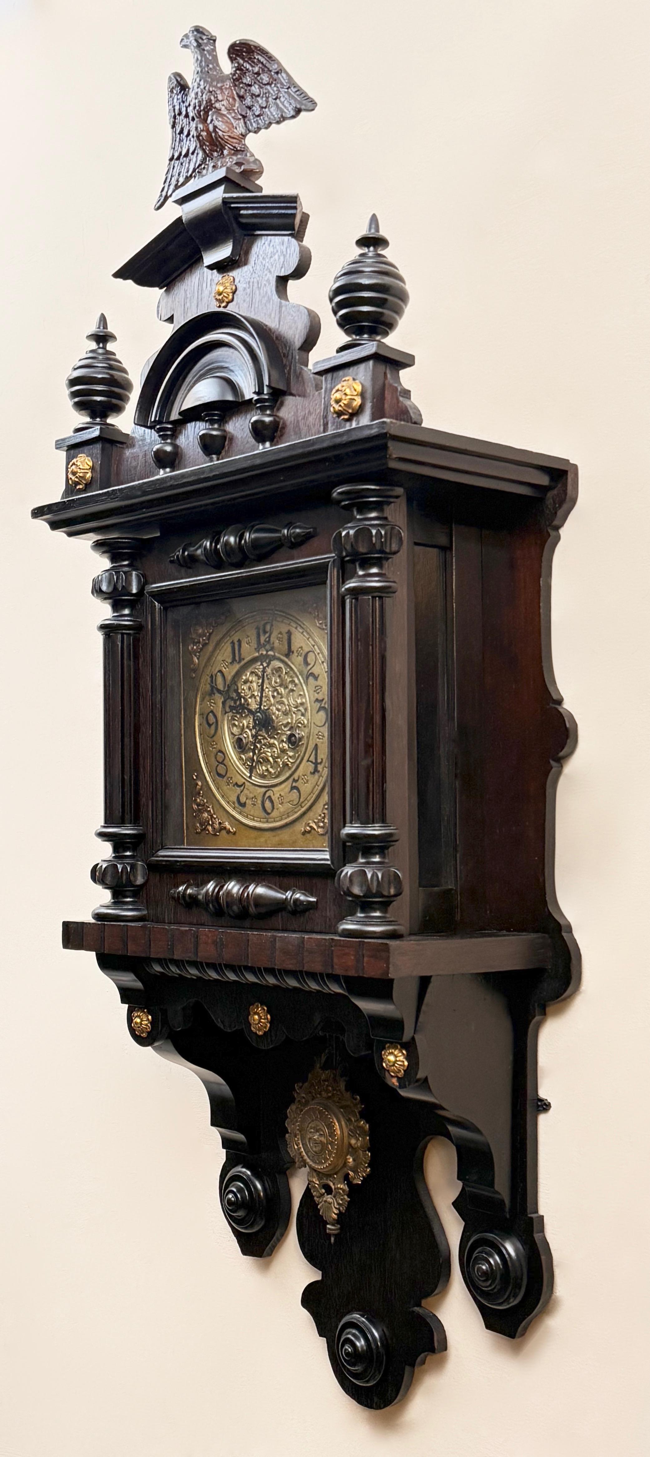 Dekoracyjny zegar ścienny zdobiony na szczycie orłem