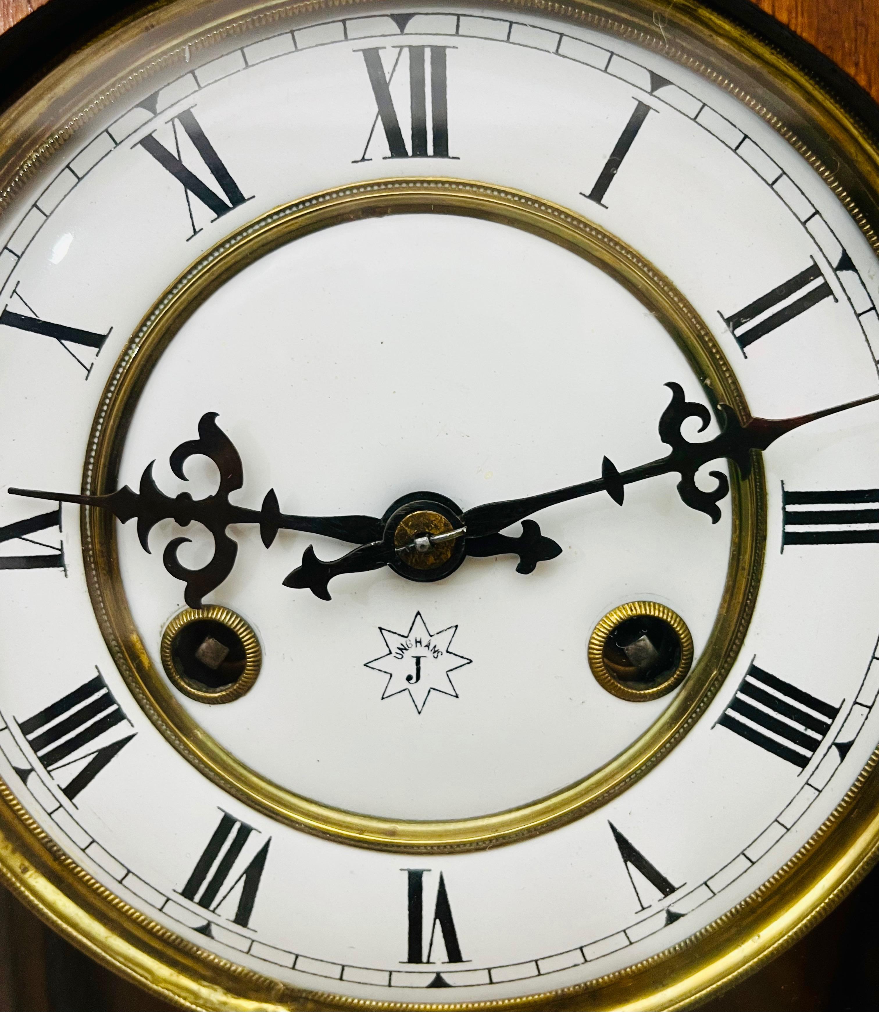 Dekoracyjny zegar ścienny zdobiony po bokach hebanowymi półfilarami