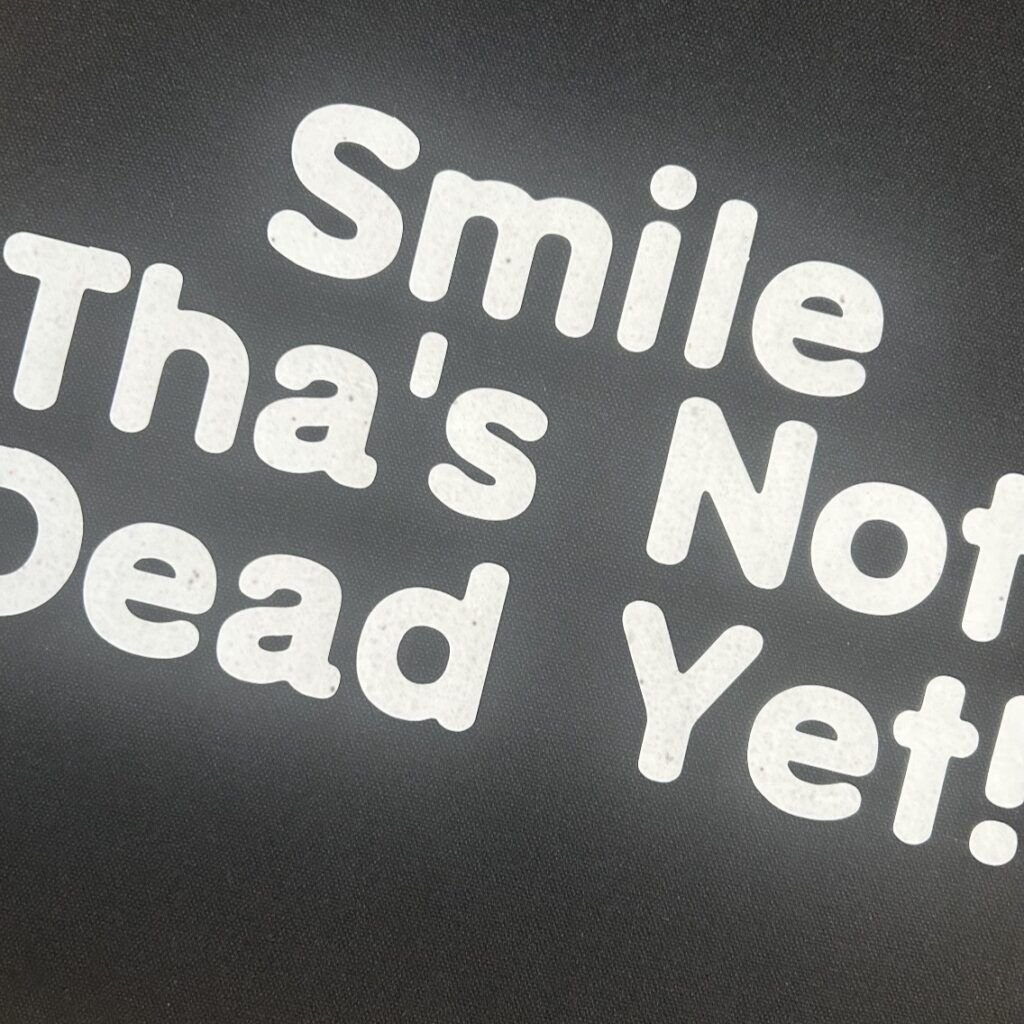 Black Tote with Smile Thas Not Dead Yet slogan, shopper,