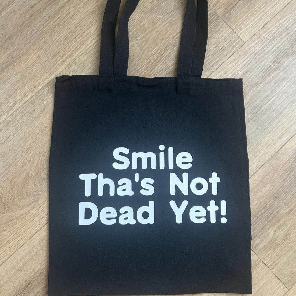 Black Tote with Smile Thas Not Dead Yet slogan, shopper,