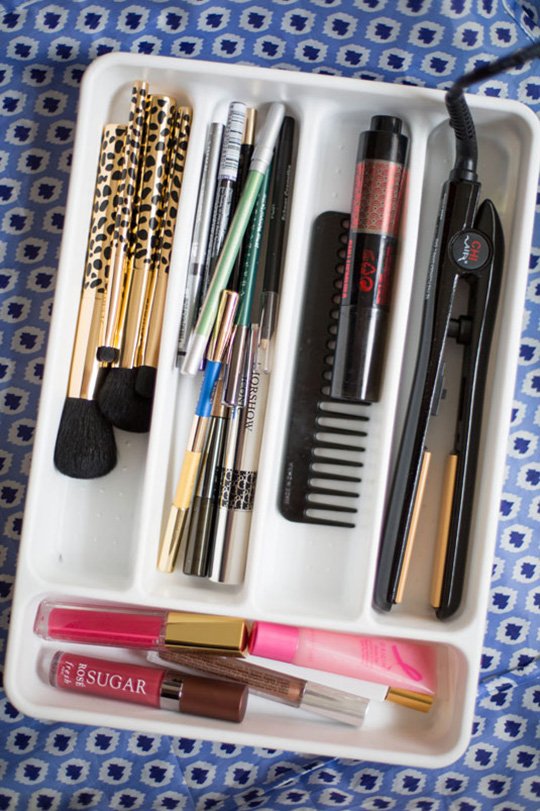 Silverware organizer being used in the bathroom to store beauty products.