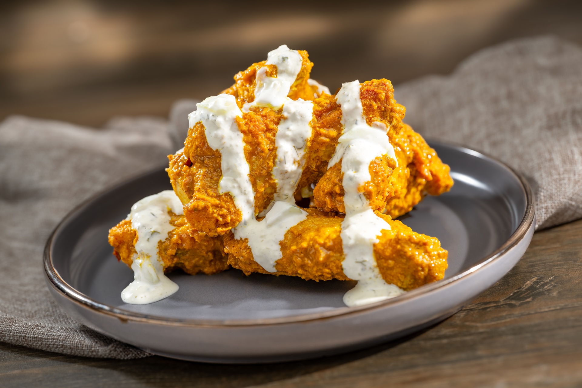 Wing Experiments, featuring Pilgrim's Jumbo Wings: Unnecessarily Spicy Yet Extremely Tasty Carolina Reaper Pepper-Curry with creamy cucumber raita, served at Brew-Wing Lab at the Odyssey during the 2026 EPCOT International Food and Wine Festival