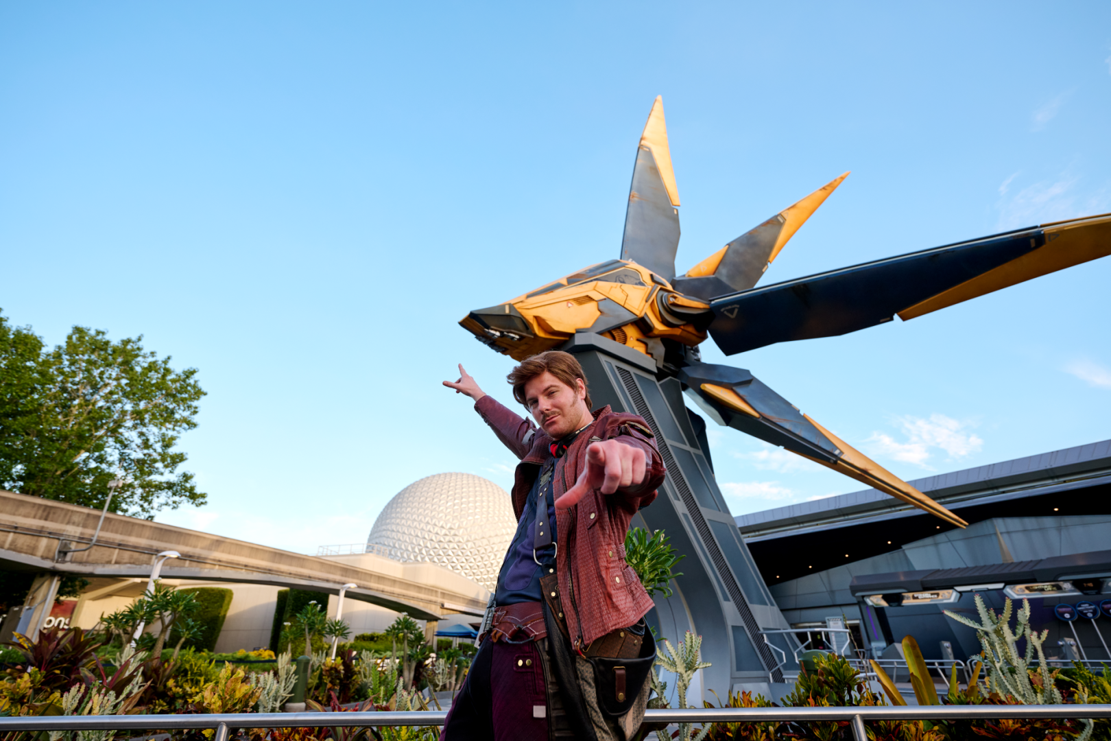 Star-Lord pointing at the camera in front of the starship sculpture outside Guardians of the Galaxy: Cosmic Rewind, with Spaceship Earth in the background