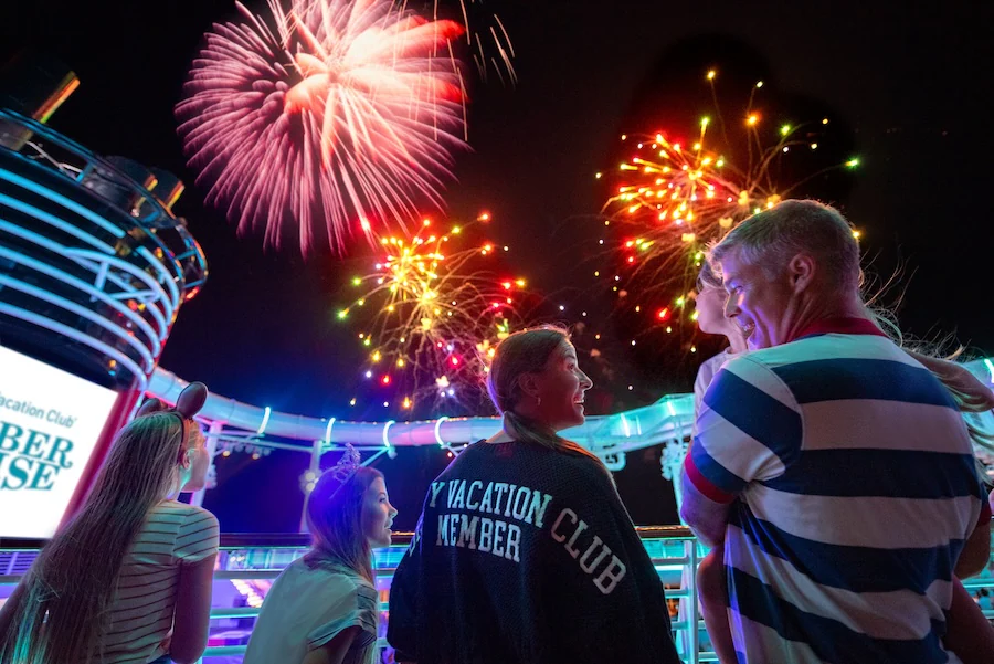 Family watching fireworks at night while on a Disney cruise