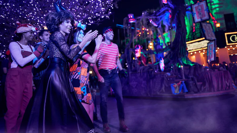 Guests wearing costumes clapping and smiling as they watch the Frightfully Fun Parade at Oogie Boogie Bash