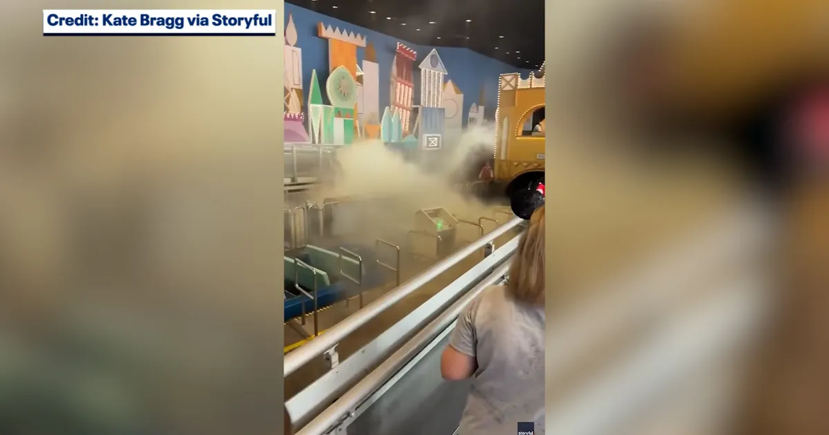 Extinguisher haze drifts across the boarding area of it's a small world at Magic Kingdom as guests look on