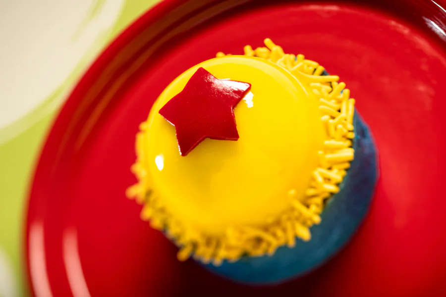 Playful Pixar Ball which is a dessert with baked vanilla cheesecake, blueberry filling and lemon almond cake.