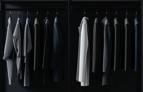 A row of clothes in shades of grey, navy, and black hanging up in a dark wardrobe.
