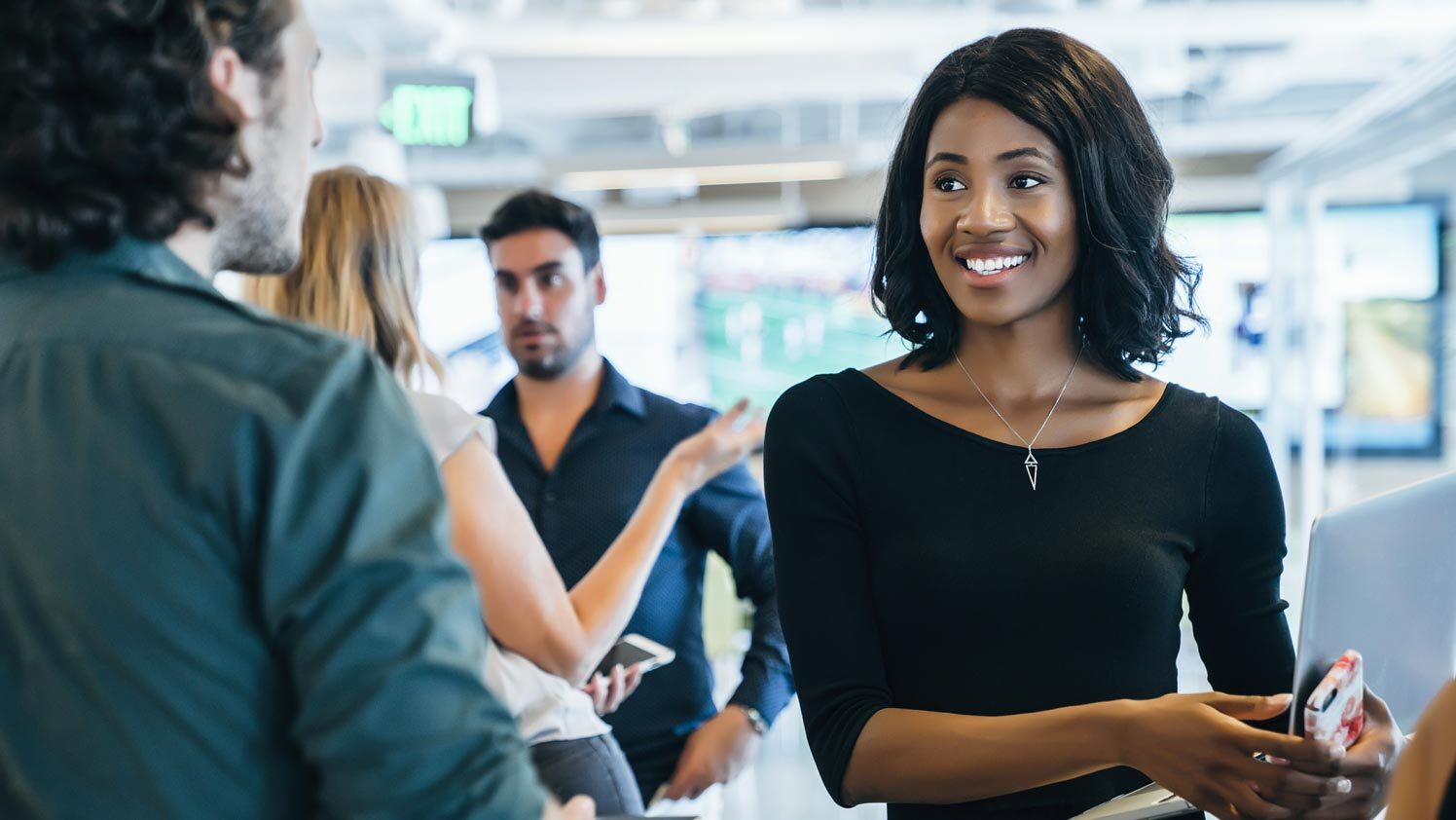 woman in a black dress meeting with a man in a green shirt in an office setting