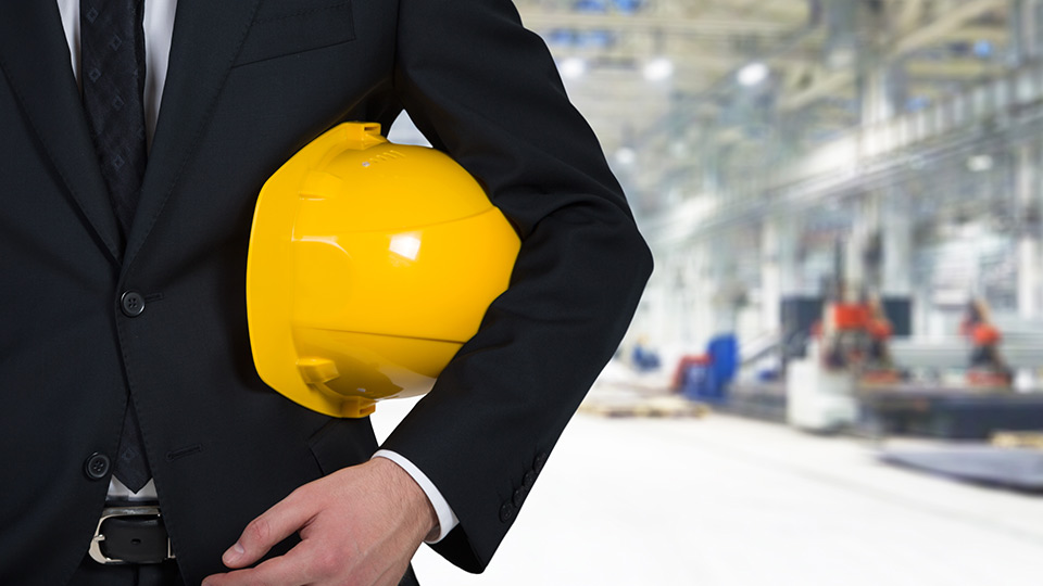 Person in suit outside holding yellow construction hat