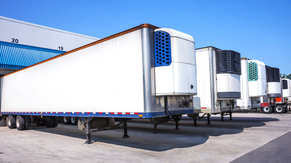 White trailers lined up side by side outside of a warehouse