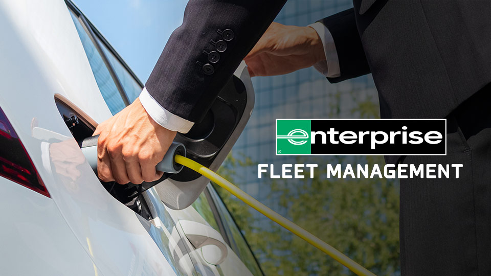 Person charging their electric vehicle with the 'enterprise fleet management' logo beside them