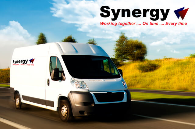 Furgoneta blanca con el logo de Synergy Courier en movimiento en una carretera