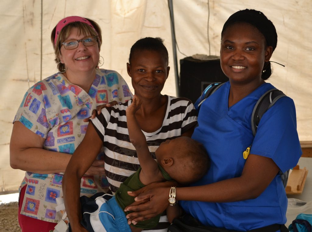 At an outreach clinic in Onaville, Haiti, Sobus teams with a Haitian nurse (right) to help a mother whose child has cerebral palsy.