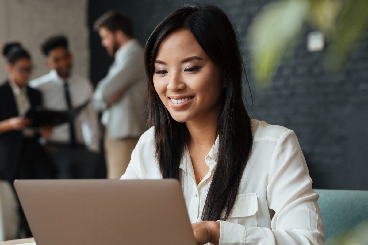 cheerful-young-asian-businesswoman-using-laptop