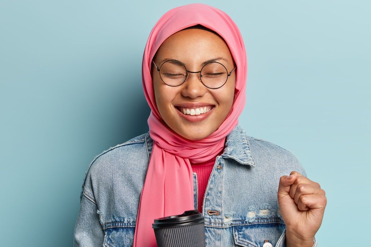 optimistic-lovely-muslim-woman-clenches-fist-closes-eyes-from-pleasure