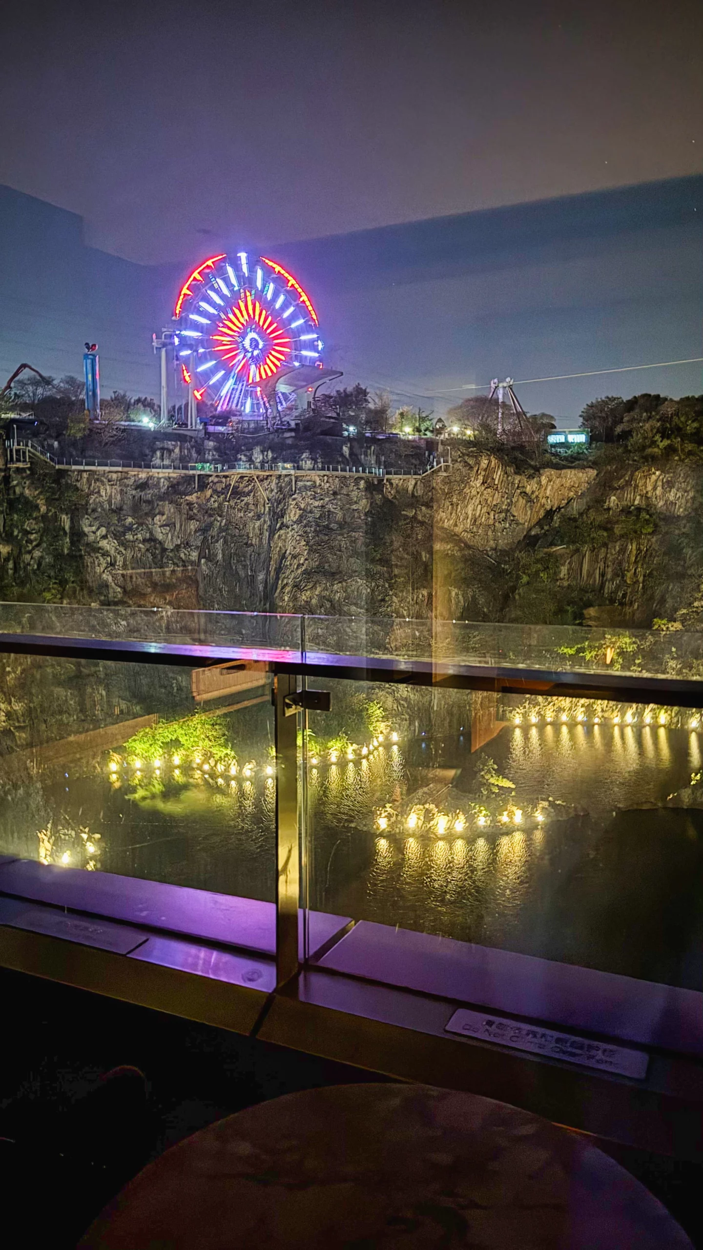 Illuminated hotel exterior at night seen from a balcony.